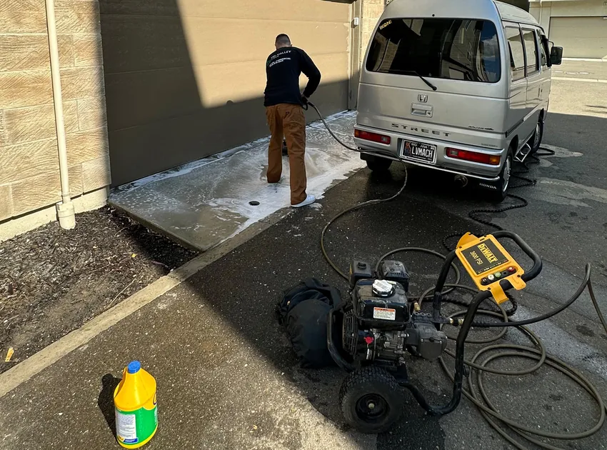 Pressure washing a driveway, with our silver Honda Acty van parked at the job