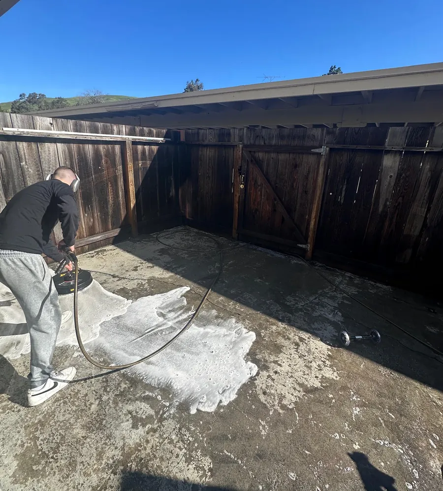 Our team pressure washing a backyard patio