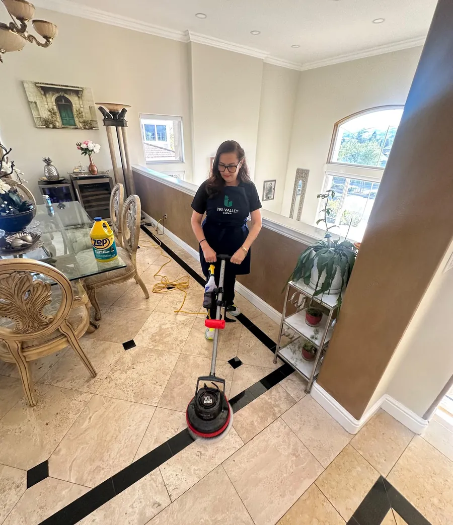 A Tri-Valley Clean team member scrubbing tile floors in a bright Tri-Valley home