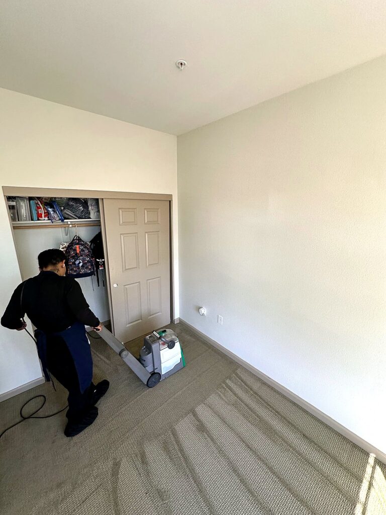 Technician deep cleaning carpet with an extraction machine